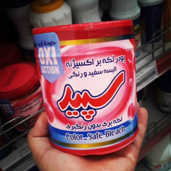 پودر لکه بر البسه سفید و رنگی 500 گرمی سپید در کف دست یک متشری کنار شونده های دیگر