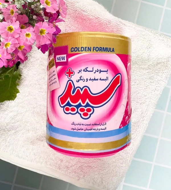 پودر لکه‌ بر سپید با فرمولاسیون طلایی (Golden Formula) در بسته‌ بندی جدید، قرارگرفته روی حوله سفید در کنار گل‌ های صورتی، مناسب شست‌ و شوی لباس‌ های سفید و رنگی، ایده‌ آل برای تمیزی عمیق