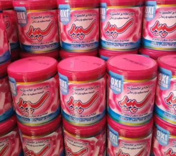 ردیف‌ محصولات پودر لکه بر سپید مدل Oxi Action با بسته‌ بندی رنگارنگ، مناسب لباس‌ های سفید و رنگی، چیده شده در قفسه فروشگاه برای خرید عمده یا تکی